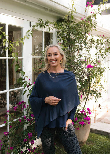 Middle aged woman smiling and posing wearing Lou Lou's Navy Blue Bamboo Poncho outside