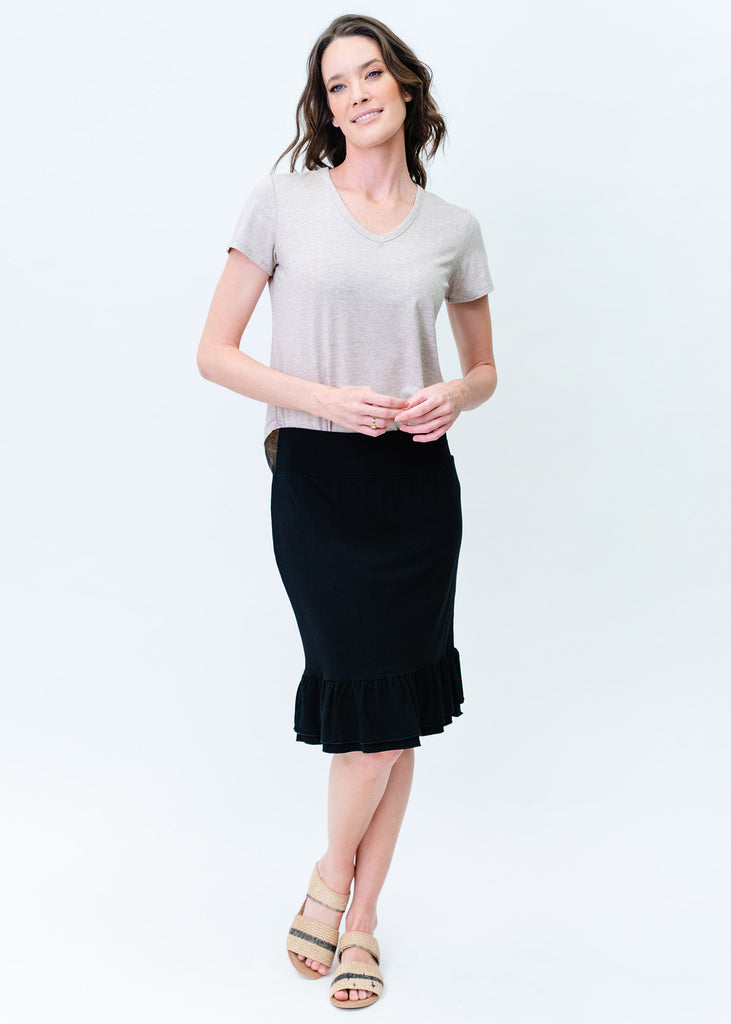 A model wearing a v-neck top and a black midi skirt paired with a taupe flat sandals, showing a simple yet relaxed fit (Product image)