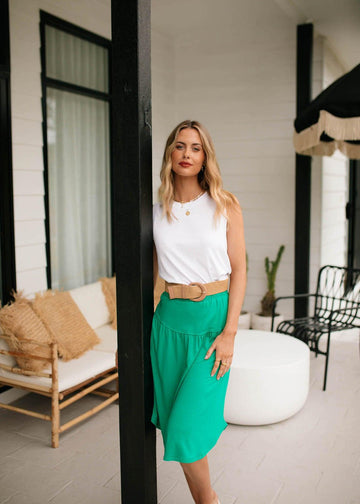 An outdoor shot of a woman in the porch while wearing a sleeveless top and emerald green midi skirt (Product image)