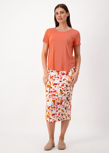 A woman modelling Lou Lou's Orange bamboo tee partnered with a floral midi skirt