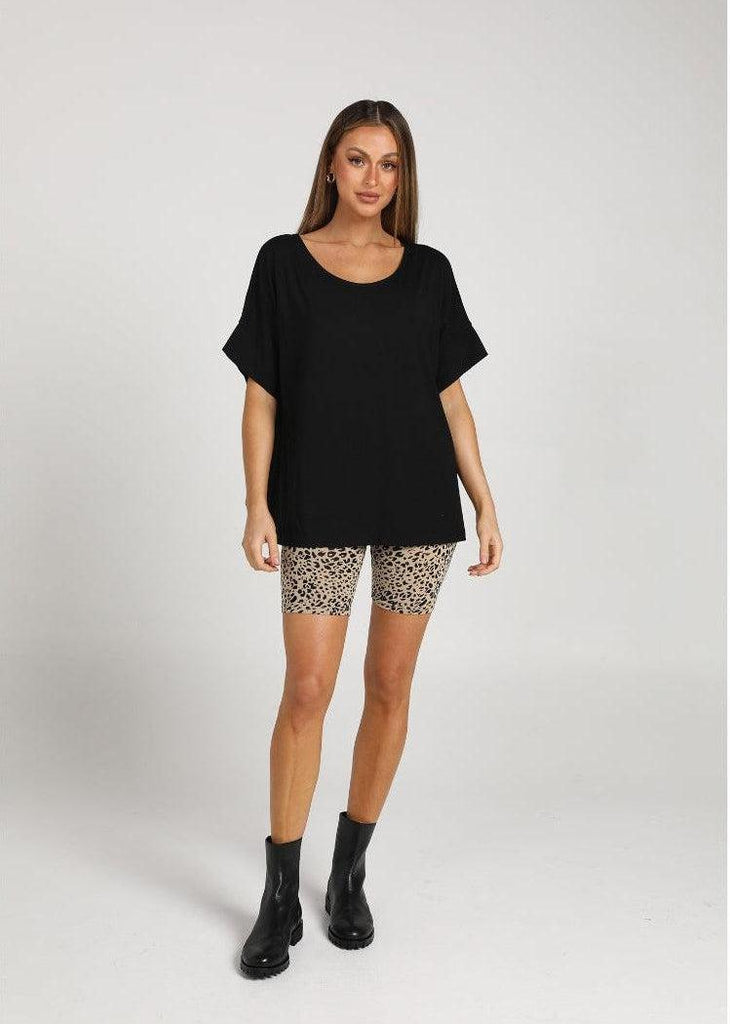 Katie Shannon wearing an oversized black bamboo tee, animal printed bike shorts & a pair of black boots