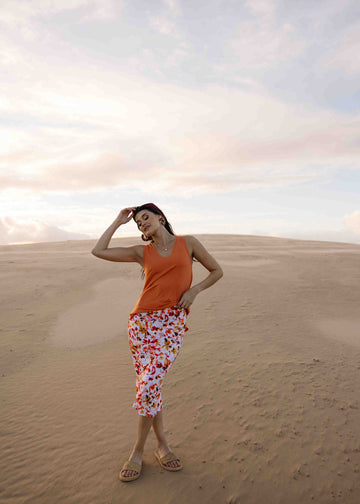 Woman posing in a dessert background wearing Lou Lou's Orange Bamboo Sleeveless Top