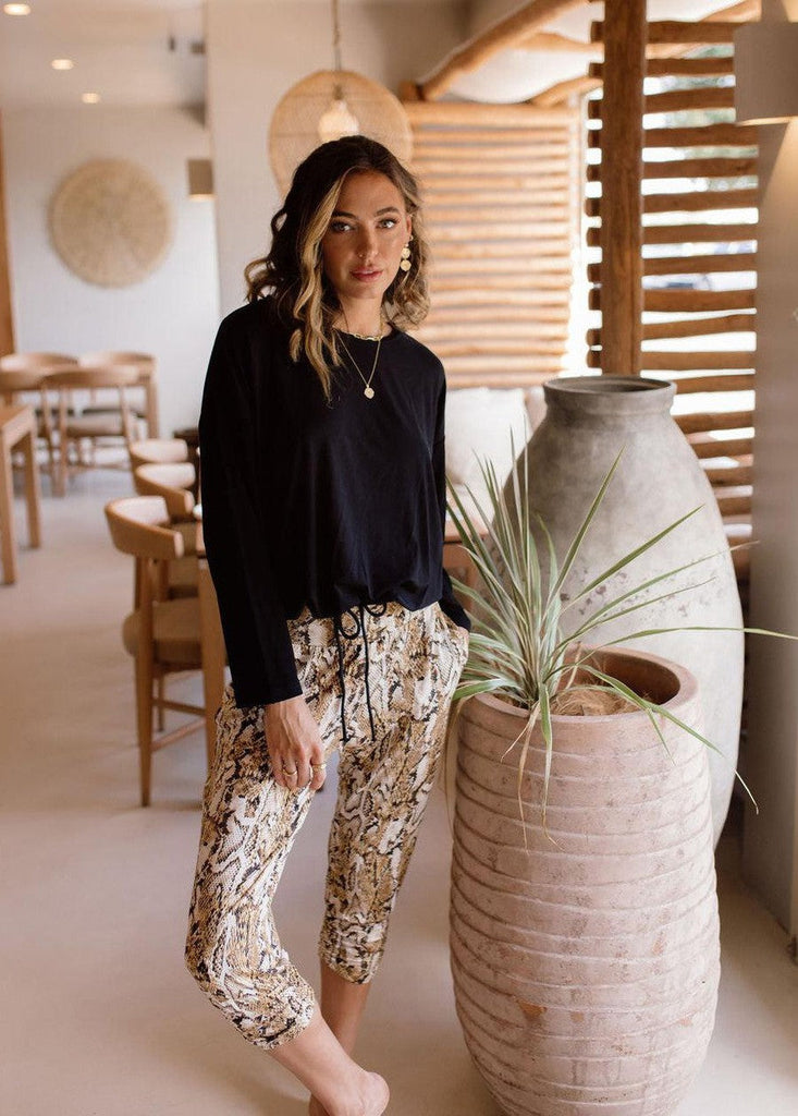 Indoor photoshoot of a model wearing black drawstring bamboo sweater and an animal printed pants (Product image)