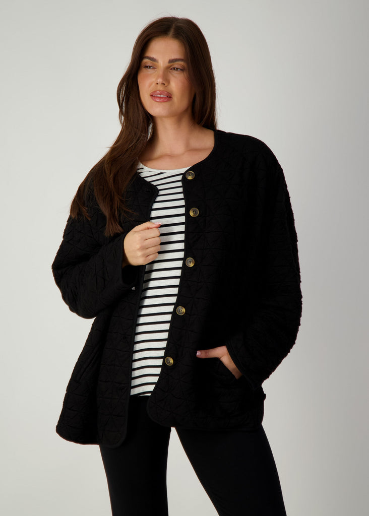 A woman modelling while wearing a quilted black oversized jacket over a striped top and black pants (Product image)