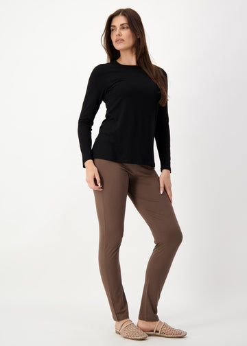 A woman standing in grey backdrop while wearing a black long sleeve top, a brown full length bamboo pants and a brown flat sandals (Product image)